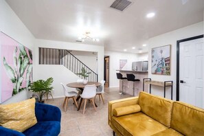 A modern living room with a staircase, a dining area, and a kitchen. - Art Deco 3 BR Near Fort Bliss (El Paso)