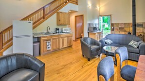 A spacious living area with a kitchen, wooden staircase, and a stone fireplace. - The River House' w/ Deck, on McKenzie River! (Springfield)