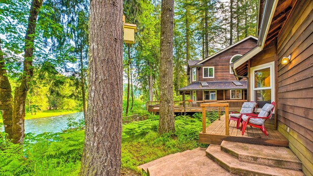 A wooden cabin with a deck and outdoor seating area overlooking a river and forest. - The River House' w/ Deck, on McKenzie River! (Springfield)
