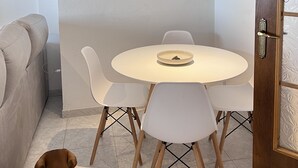 Ein Essbereich mit einem runden Tisch, weißen Stühlen und Holzboden.