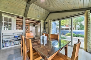 A spacious dining area with a glass table and wooden chairs, a wooden ceiling, and a view of the outdoors.