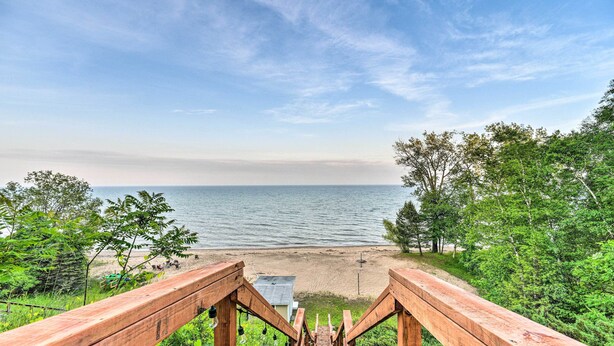 Puinen portaikko, joka johtaa rannalle, josta avautuu näkymä merelle ja puustolle.