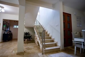 Staircase leads to an upper level, flanked by white walls and a wooden door with glass panels.