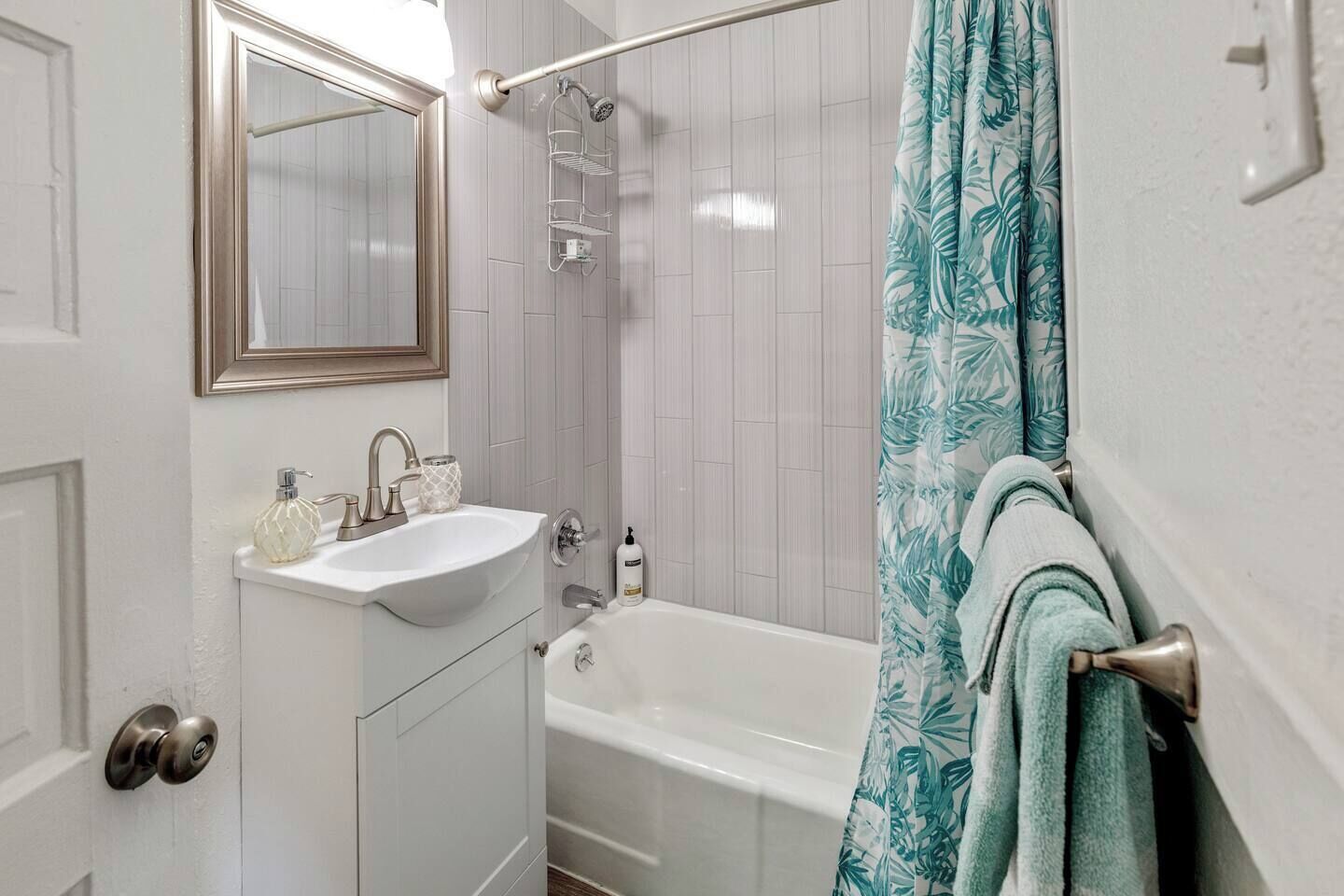 Une salle de bain avec un lavabo blanc, un miroir et une baignoire.