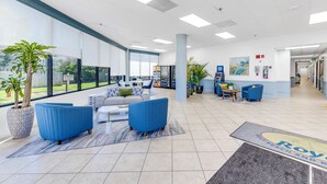 Un vestíbulo amplio con zona de estar, ventanas grandes y mostrador de recepción.