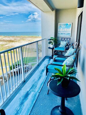 A balcony with a view of the beach, two chairs with cushions, a small table, and a potted plant. - Refresh, Relax, and Recharge!  Family-sized Resort Beach condo. (Gulf Shores)