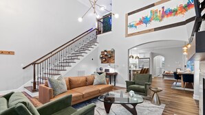A spacious living area with a staircase, a dining area, and a kitchen. - 3min to Aquarium | Secret Game Room | 3 King Beds (Chattanooga)