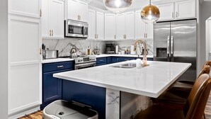 A modern kitchen with white cabinetry, a central island, stainless steel appliances, and a unique spherical pendant light. - 3min to Aquarium | Secret Game Room | 3 King Beds (Chattanooga)