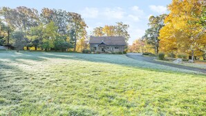 Une maison avec une cour verdoyante et des arbres aux feuilles d’automne.