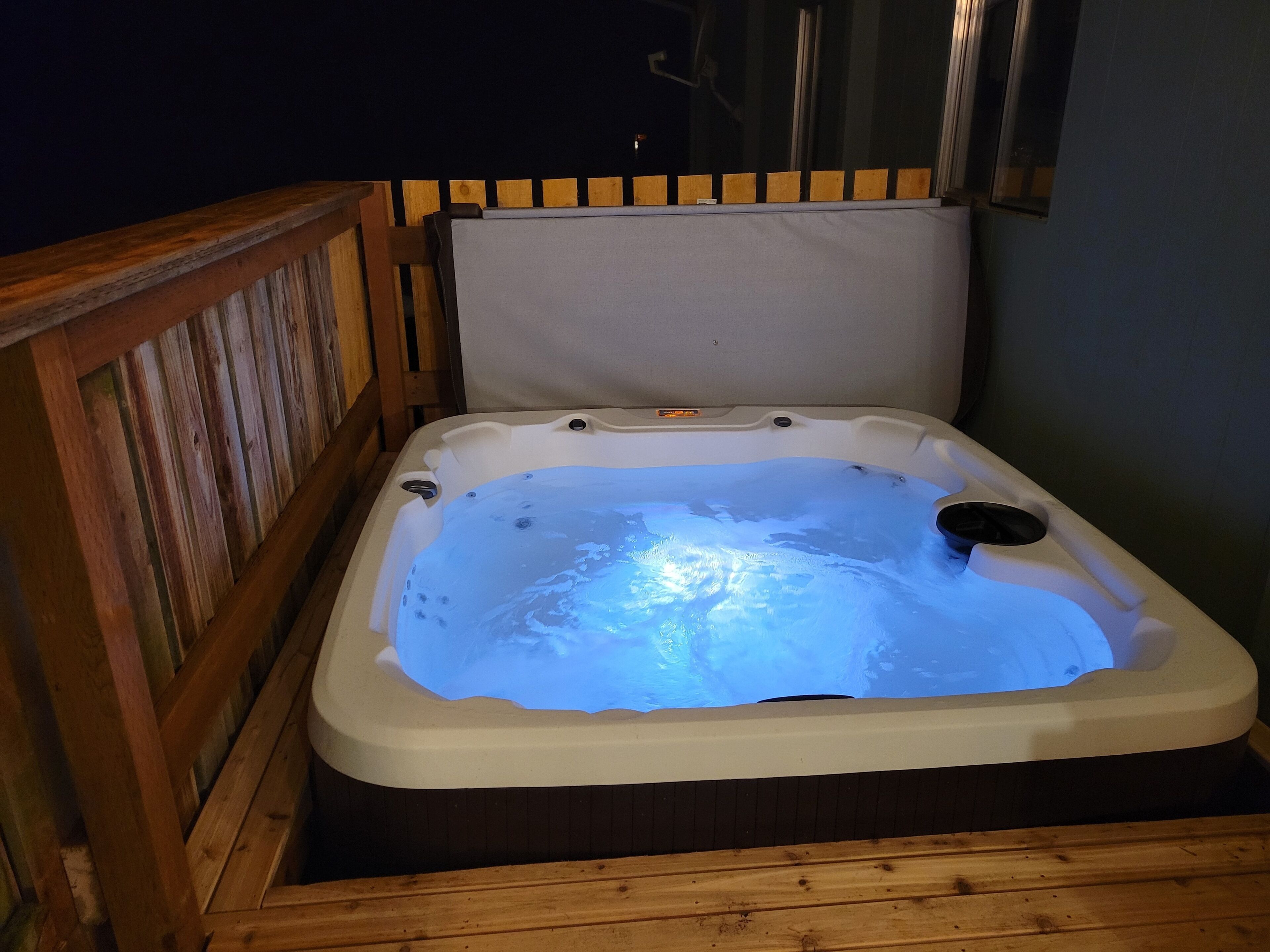 Ett bubbelbad med ett trädäck och ett fönster.
