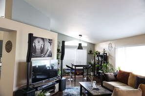 Relax in this inviting living room with a flat-screen TV, dining table, and comfortable sofa.