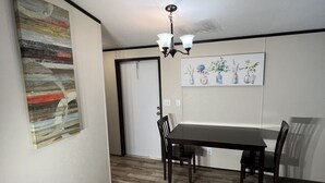A dining area with a wooden table and chairs, a chandelier, and a painting on the wall.