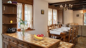Ein Essbereich mit einem Holztisch, gedeckt für vier Personen, einer Blumenvase und einer Obstschale auf der Arbeitsfläche.