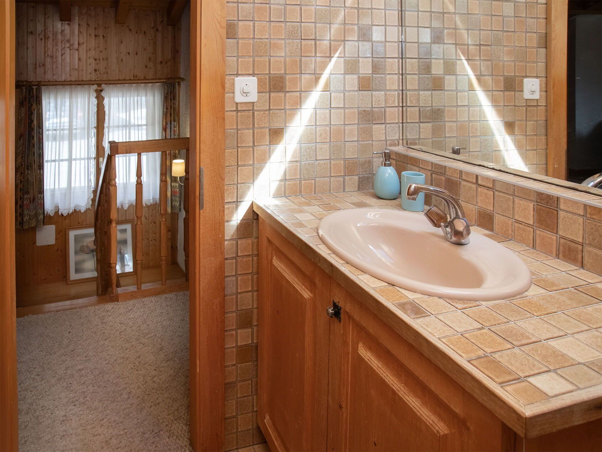 A bathroom with a wooden vanity, a sink, and a mirror.
