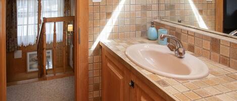 A bathroom with a wooden vanity, a sink, and a mirror.