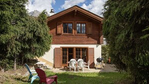 Eine Holzhütte mit Terrasse, umgeben von Bäumen und einem Berg im Hintergrund.