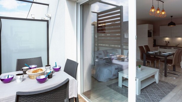 A modern apartment with a balcony, a dining area, and a kitchen. - Cosy apartment for 4 guests with WIFI, TV and terrace (St-malo)