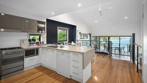 Une cuisine moderne dotée d’un grand îlot central, d’appareils électroménagers en acier inoxydable et donnant sur un balcon.
