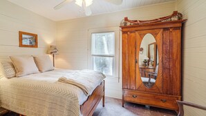Ein Schlafzimmer mit einem Bett, einem Holzschrank, einem Deckenventilator und einem Fenster.