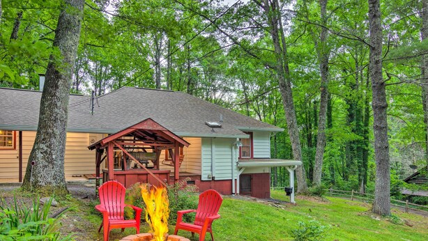 Ein Haus mit Feuerstelle und zwei roten Adirondack-Stühlen im Garten.