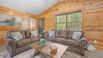 A cozy living room with two brown leather sofas, a wooden coffee table, and a patterned rug.