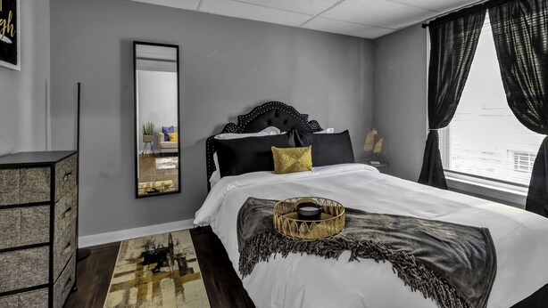 A bedroom with a large bed, a dresser, a mirror, and a window with curtains. - EXPLORE & RELAX Heart of the city,NEAR EVERYTHING! (Buffalo)