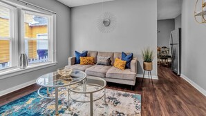A living room with a grey sofa, two glass coffee tables, a patterned rug, and a dining area in the background. - EXPLORE & RELAX Heart of the city,NEAR EVERYTHING! (Buffalo)