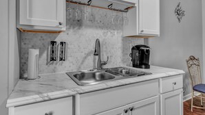 A kitchen with white cabinets, a marble countertop, a stainless steel sink, a coffee maker, and a wine rack. - EXPLORE & RELAX Heart of the city,NEAR EVERYTHING! (Buffalo)