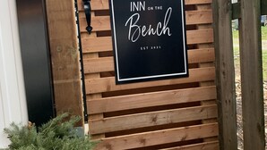 Une porte en bois sur laquelle est apposée une plaque indiquant : « INN ON THE Bench, fondé en 2021 ».