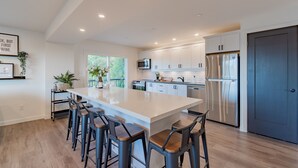 Une cuisine moderne dotée d’un grand îlot central, d’appareils électroménagers en acier inoxydable et de tabourets de bar.