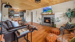 A spacious living room with a leather sofa, a fireplace, and a television. - Private cabin with amenities ⭐️Location⭐️Spa Pool⭐️Hot tub⭐️Firepit⭐️Pets (Sevierville)