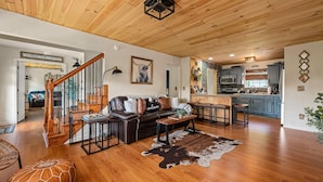 A spacious living room with a wooden ceiling, a leather sofa, a coffee table, and a cowhide rug. - Private cabin with amenities ⭐️Location⭐️Spa Pool⭐️Hot tub⭐️Firepit⭐️Pets (Sevierville)