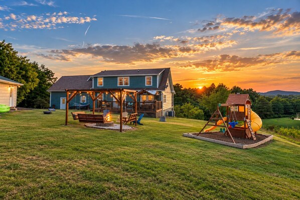 A house with a deck, a swing set, and a playhouse.