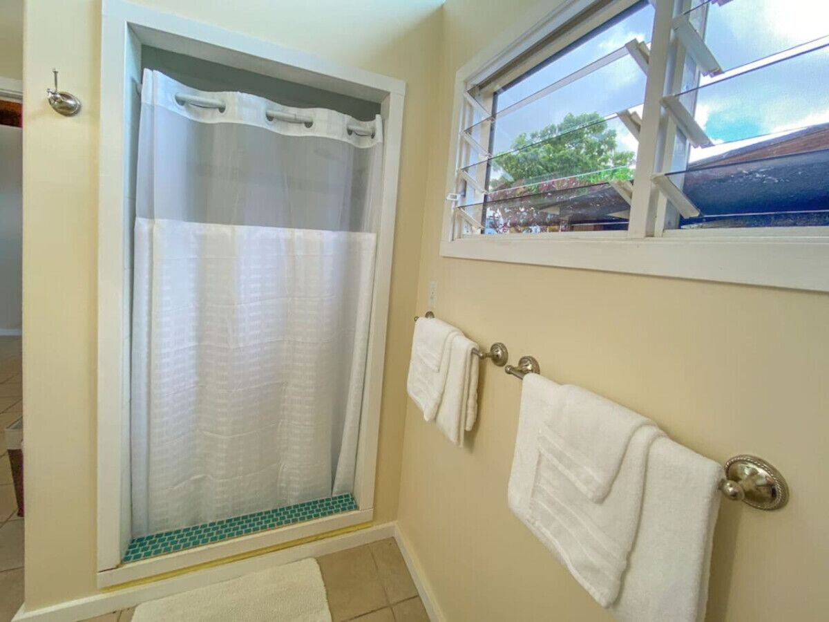 A bathroom with a shower, a window, and a towel rack with towels.