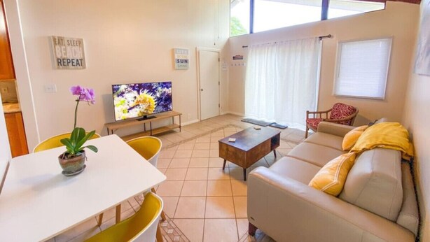 En stue med sofa, sofabord, fjernsyn og en loftventilator.