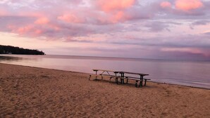 Una playa con una mesa de picnic de madera y bancos.