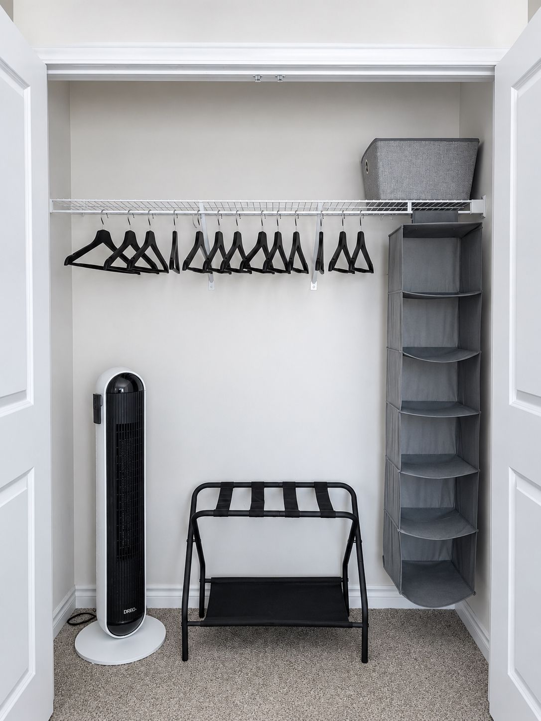 A closet with a hanging rack, shelves, and a storage unit.