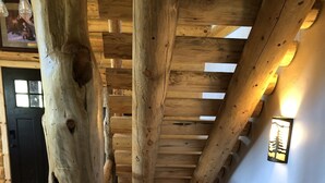 A wooden staircase with a rustic design, a wooden door, and a wall-mounted light fixture. - Private Log Cabin with breathtaking views on 15 acres adjacent to forest service (Council)