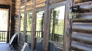 A log cabin with a wooden deck, large windows, and outdoor seating. - Private Log Cabin with breathtaking views on 15 acres adjacent to forest service (Council)