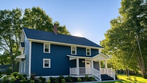 Ein zweistöckiges Haus mit einer Veranda und einer Treppe, die zum Eingang führt.