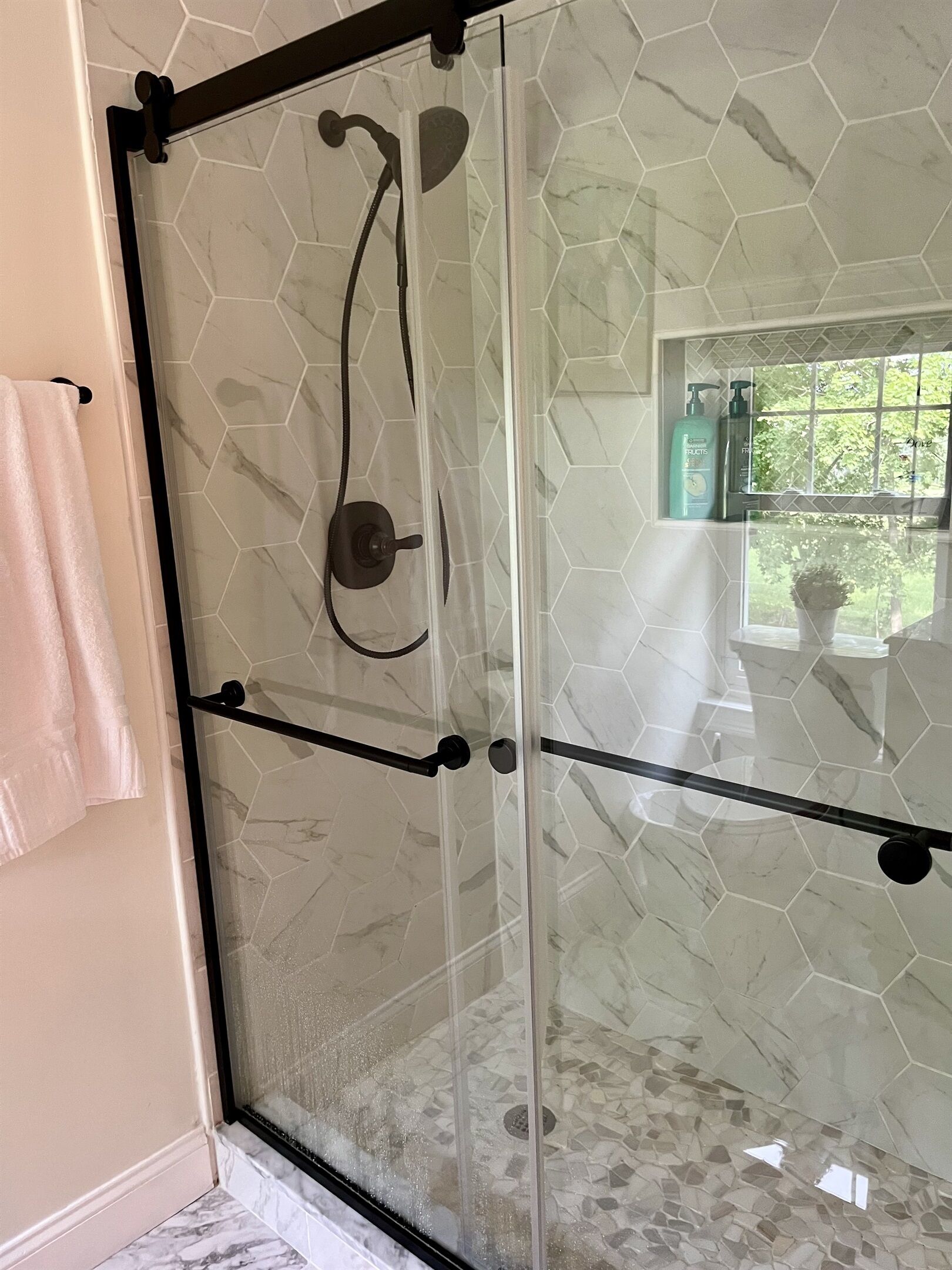 Une douche avec une porte en verre et un pommeau de douche à effet pluie.