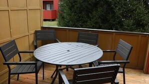 A round metal table with four chairs, set on a wooden deck with a wooden fence and a green hedge in the background. - Athens city townhouse, 3 bedrooms, 2.5 baths, FREE Wi-Fi, FREE Parking, Deck, 18 (Athens)
