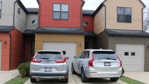 Two parked SUVs in a driveway with a garage and a red house in the background. - Athens city townhouse, 3 bedrooms, 2.5 baths, FREE Wi-Fi, FREE Parking, Deck, 18 (Athens)