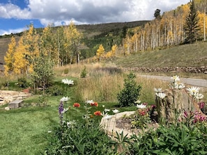 A garden with various flowers and a stone wall.