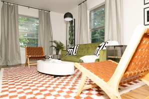 Relax in this stylish living room with a green sofa, round coffee table, and woven chair.