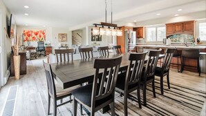 A modern kitchen with a large dining table, wooden cabinets, and pendant lighting. - Castle Farms wedding weekend, 7BR (Charlevoix)
