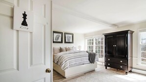 A bedroom with a bed, a dark wooden cabinet, and a door with a chess piece decoration. - Castle Farms wedding weekend, 7BR (Charlevoix)