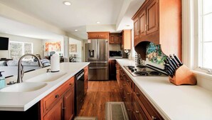 A modern kitchen with wooden cabinets, stainless steel appliances, and a large island with a sink. - Castle Farms wedding weekend, 7BR (Charlevoix)