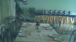 A dining area with a long table set for four, surrounded by chairs. - Gulf Hotel (Karachi)