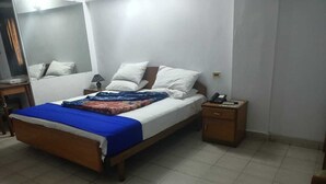 A bedroom with a bed, bedside table, and a nightstand. - Gulf Hotel (Karachi)
